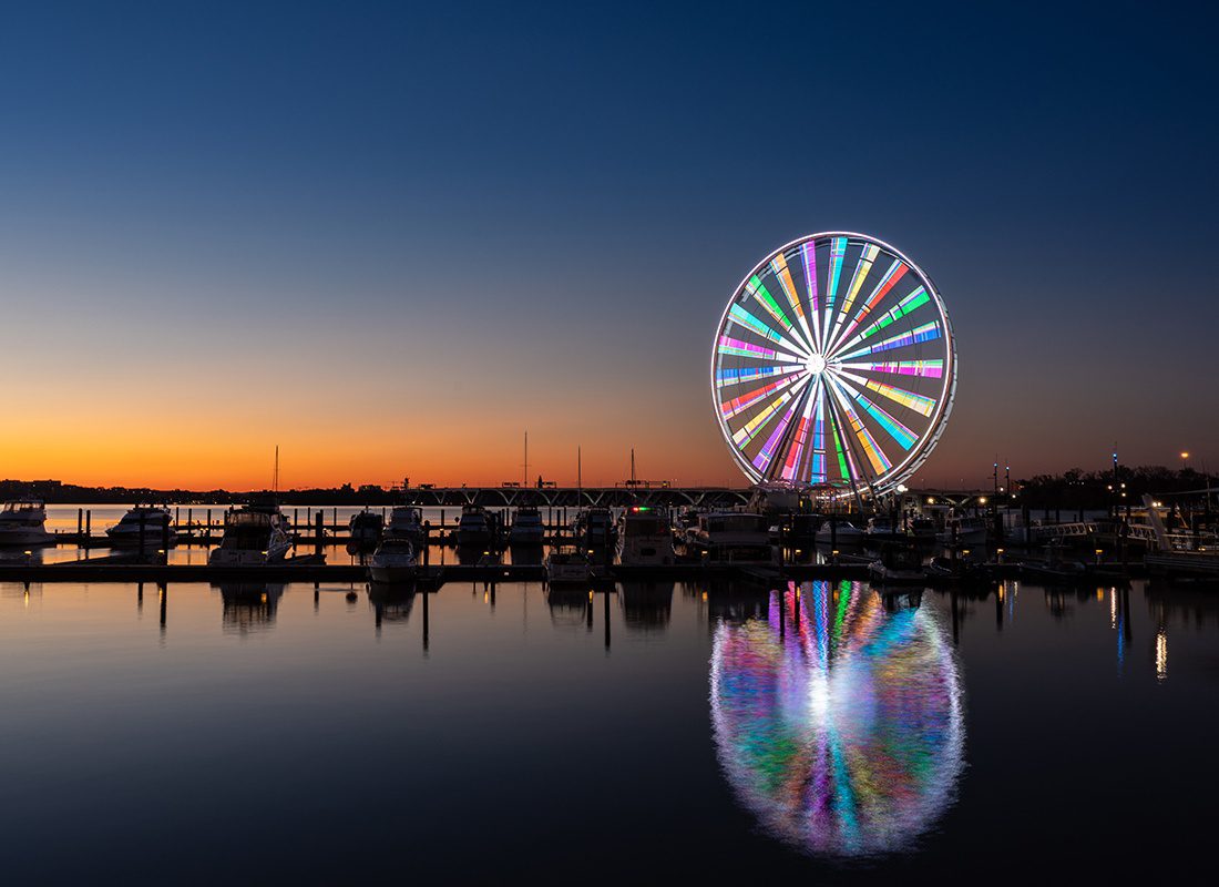 Blog - Blog - Bright Ferris Wheel Spins and Shines Reflection Onto Lake During the Evening