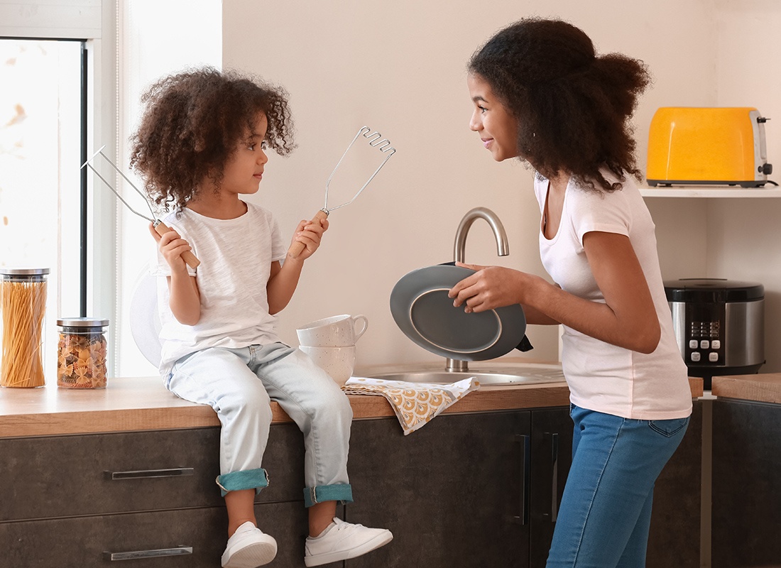 Personal Insurance - Little Girl and Big Sister Wash Dishes Together at Home